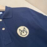 Maglietta polo navy con logo ricamato in crema, tessuto testurizzato, stile casual ed elegante.