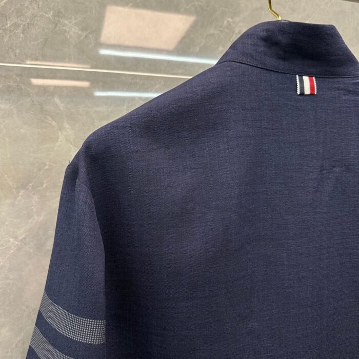 Camicia navy con dettaglio a strisce e emblemle nazionale, stile moderno e sofisticato.