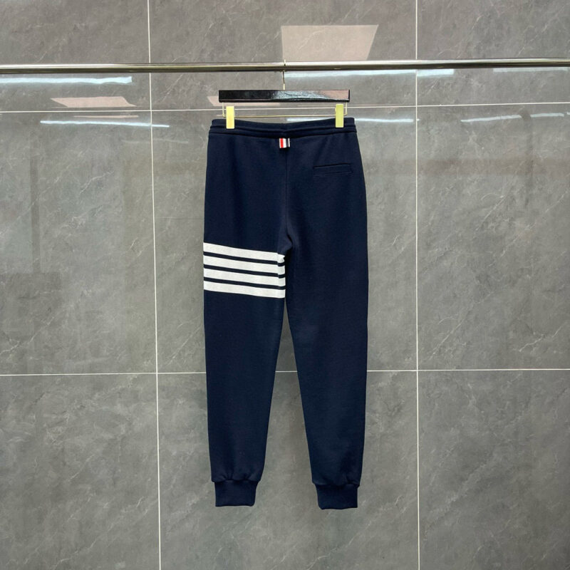 Pantaloni jogger navy blu con bande bianche, stile sportivo e comfort, su sfondo grigio.