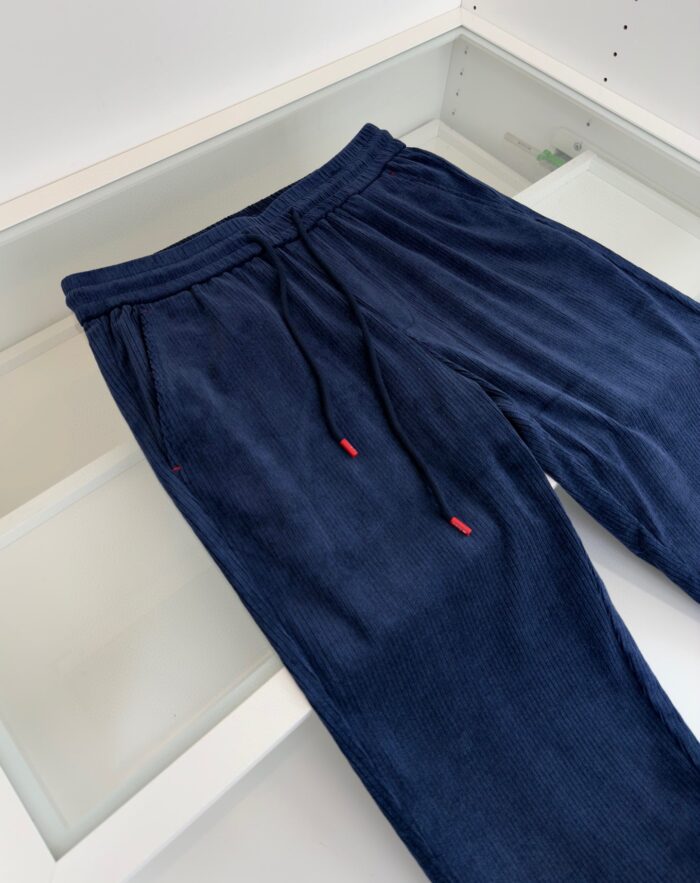 Pantaloni jogger navy con vita elastica, tasche nascoste e lacci rossi, ideali per relax e sport.