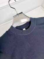Felpa nera casual con collo a costine, elegante e comoda, su appendiabiti trasparente.