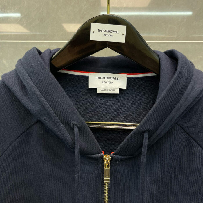 Felpa navy Thom Browne con zip, dettagli di lusso, stile moderno e alta qualità.