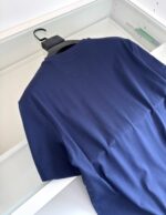 Maglietta blu navy classica in cotone, elegante e versatile, appesa su gruccia bianca.