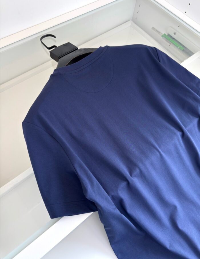 Maglietta blu navy classica in cotone, elegante e versatile, appesa su gruccia bianca.