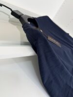 Maglietta blu navy elegante su appendiabiti moderno, tessuto morbido e finitura raffinata.