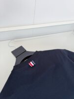 Maglietta navy blue con etichetta minimalista e stile moderno su sfondo neutro.