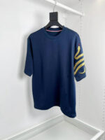 T-shirt navy blue con grafica gialla astratta sulla manica, stile casual e moderno.