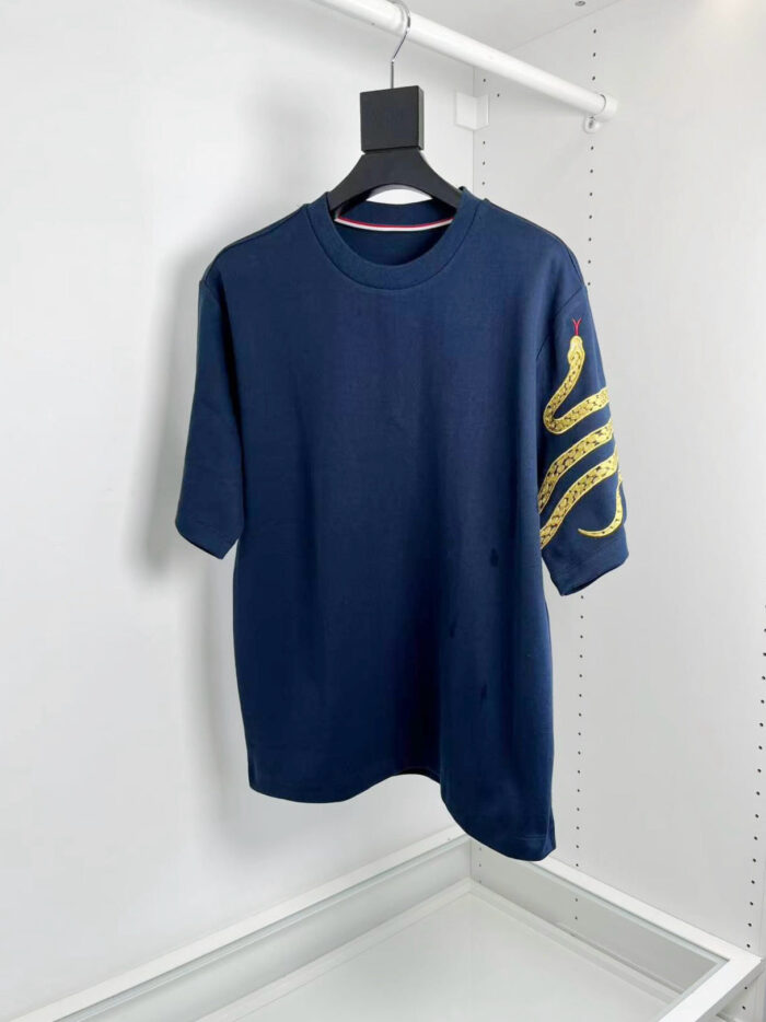 T-shirt navy blue con grafica gialla astratta sulla manica, stile casual e moderno.