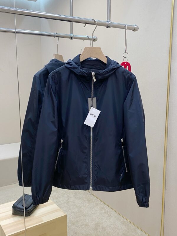 Giaccone blu navy leggero con cappuccio, tasche con zip e stile comunque moderno.