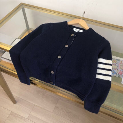Cardigan navy blu con striscia bianca e dettagli classici, stile vintage e moderno.