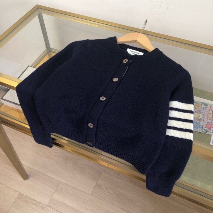 Cardigan navy blu con striscia bianca e dettagli classici, stile vintage e moderno.