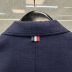 Dettaglio del colletto navy con etichetta a strisce rosso, bianco e blu, stile elegante e moderno.
