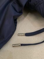 Giaccone navy con cordoncini in tessuto e aglet in metallo, stile e funzionalità moderna.