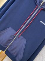 Felpa blu navy con cerniera, tasche frontali e dettagli rossi, stile sportivo casual.