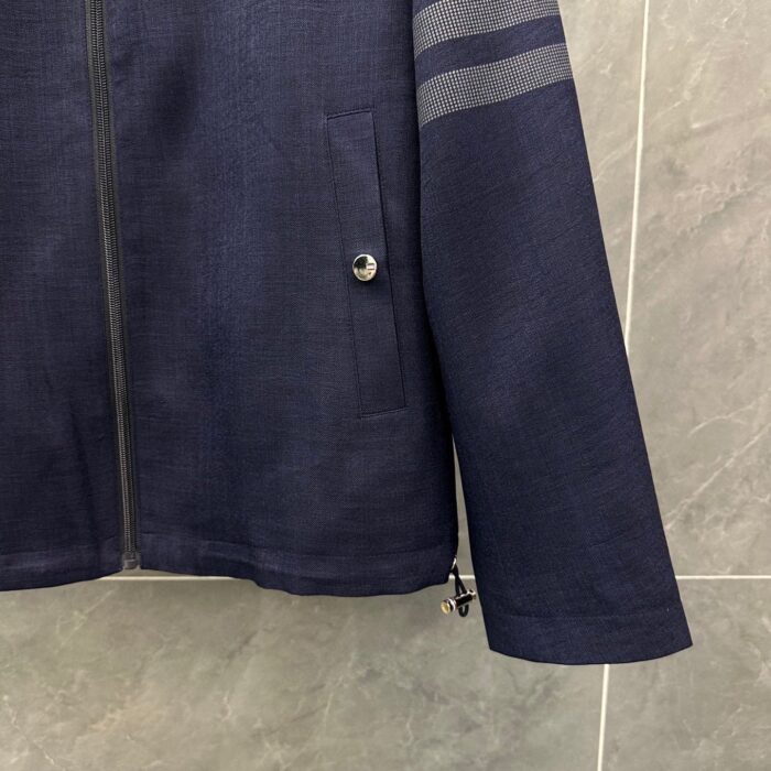 Giacca navy textured con bottoni metallici, tasca, dettagli riflettenti e design sportivo.