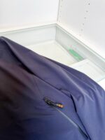 Giacchetto navy con dettaglio zip colorato in esposizione in ambiente moderno ed elegante.