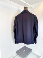 Giacca navy uomo elegante su appendiabiti in guardaroba minimalista e ben illuminato.