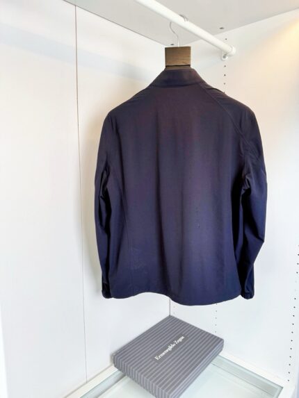 Giacca navy uomo elegante su appendiabiti in guardaroba minimalista e ben illuminato.