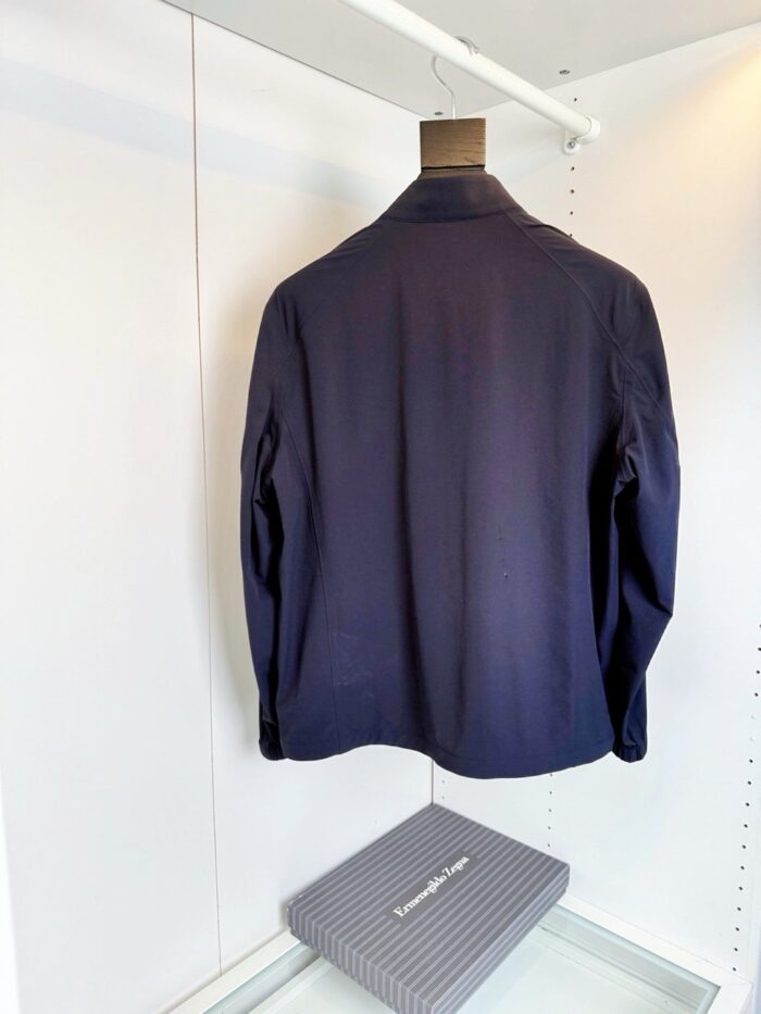 Giacca navy uomo elegante su appendiabiti in guardaroba minimalista e ben illuminato.