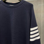 Maglione blu navy con righe bianche, collo a giro e stile sportivo casual.