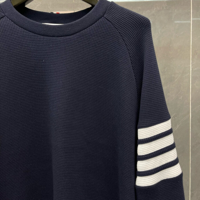 Maglione blu navy con righe bianche, collo a giro e stile sportivo casual.