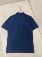 Maglietta polo navy blu su gancio di legno, stile classico e minimalista, perfetta per ogni occasione.