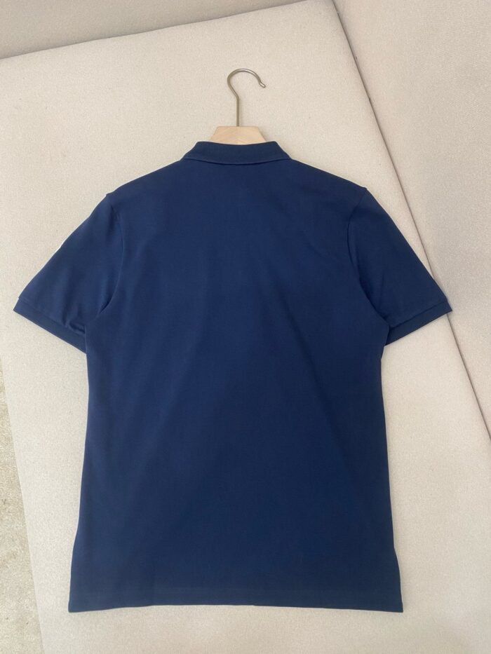 Maglietta polo navy blu su gancio di legno, stile classico e minimalista, perfetta per ogni occasione.