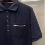 Maglietta polo navy con taschina a strisce rosso e bianco, stile classico e vestibilità elegante.