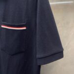 Maglietta polo navy con tasca a strisce rosso, bianco e blu, stile casual e sporty.