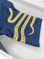 Manica navy con ricami di serpenti gialli, dettaglio serpente con lingua rossa, stile elegante e dinamico.