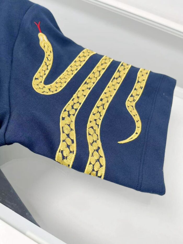 Manica navy con ricami di serpenti gialli, dettaglio serpente con lingua rossa, stile elegante e dinamico.