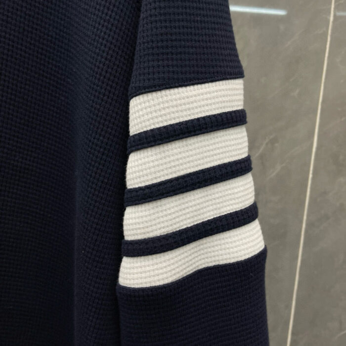 Manica a righe bianche su maglione navy, tessuto waffle, stile sportivo e elegante.