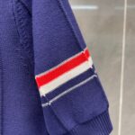 Manica di maglione navy con strisce rosse e bianche, stile sportivo e moderno.