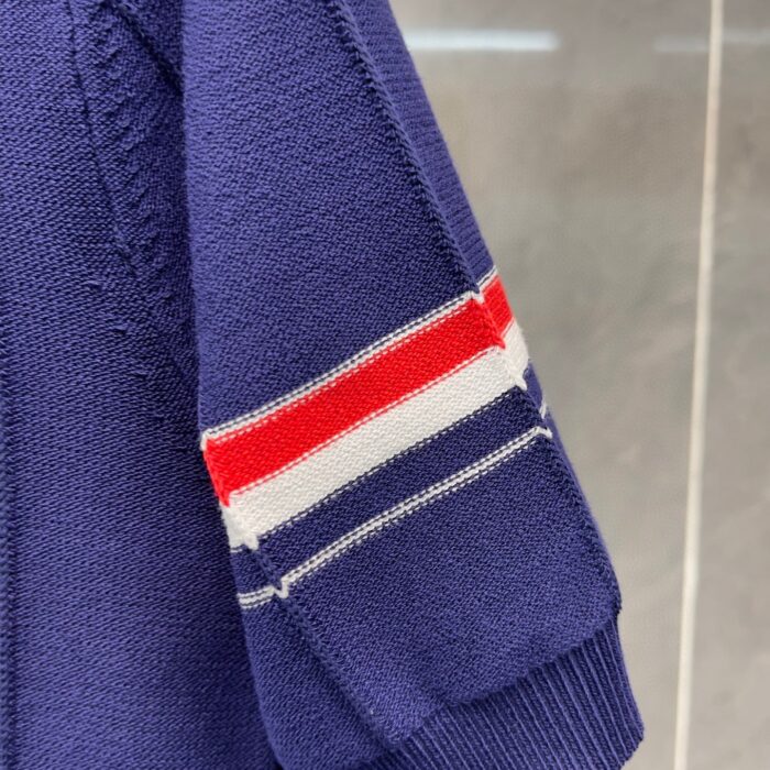 Manica di maglione navy con strisce rosse e bianche, stile sportivo e moderno.
