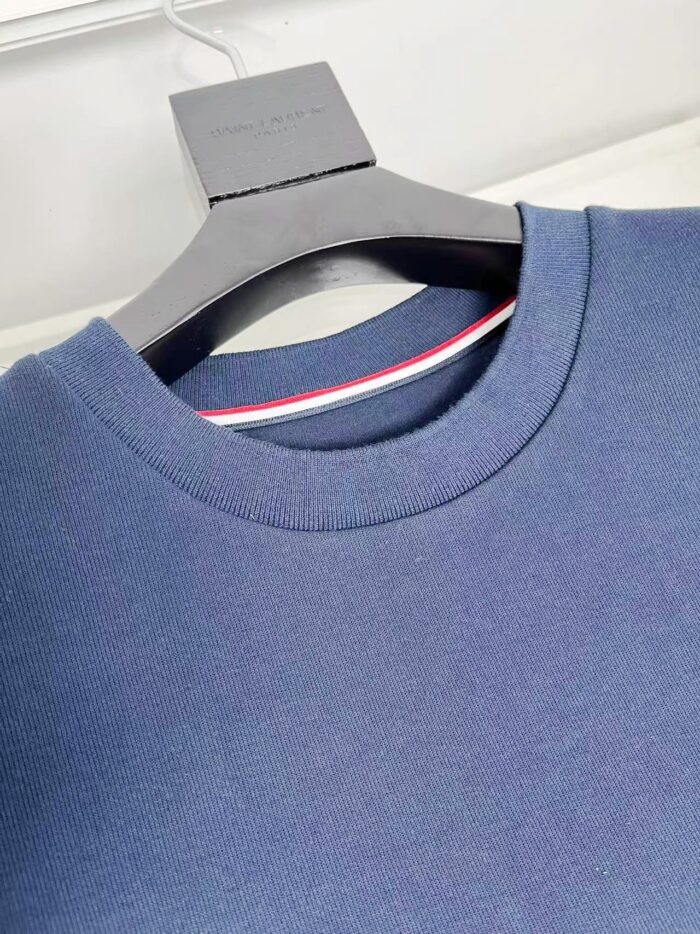 Maglione navy con dettaglio a strisce, girocollo classico e stile sportivo, su appendiabiti nero raffinato.
