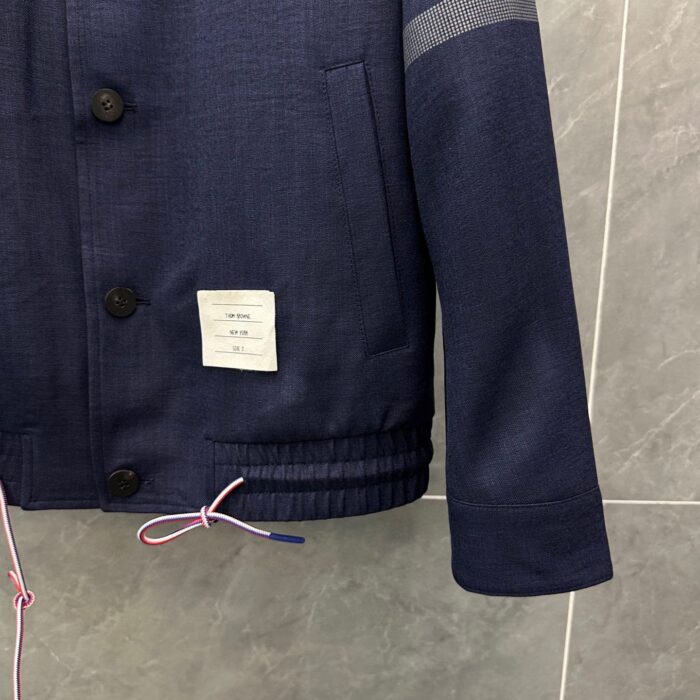 Giacca blu navy elegante con cordini rosa, bottoni classici e dettaglio con etichetta bianca.