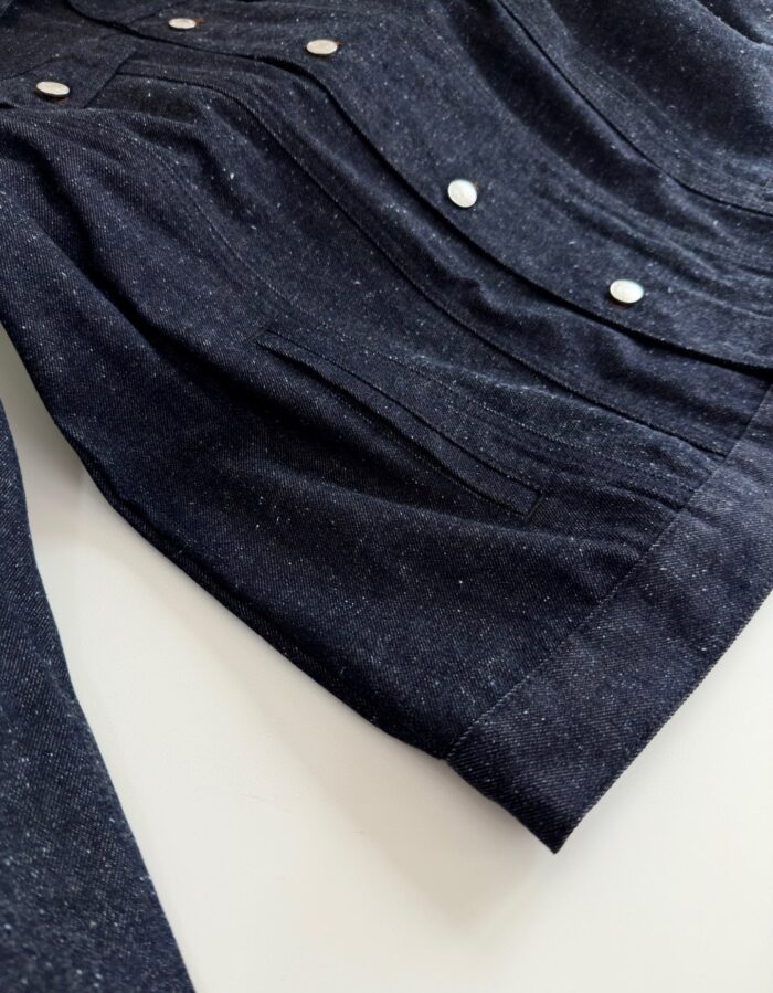 Giacca navy con bottoni metallico, dettaglio plisè e design elegante e casual.