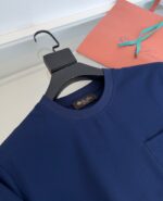T-shirt navy blu con taschino, busta decorativa e nastro blu, stile casual elegante.