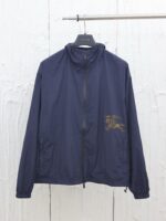 Giacca leggera navy con zip, high collar e dettaglio decorativo sul petto.