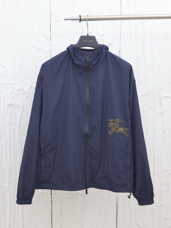 Giacca leggera navy con zip, high collar e dettaglio decorativo sul petto.