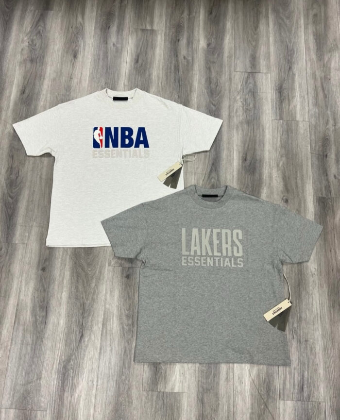 Magliette NBA Lakers casual e sportive nuove con etichette, su pavimento in legno naturale.