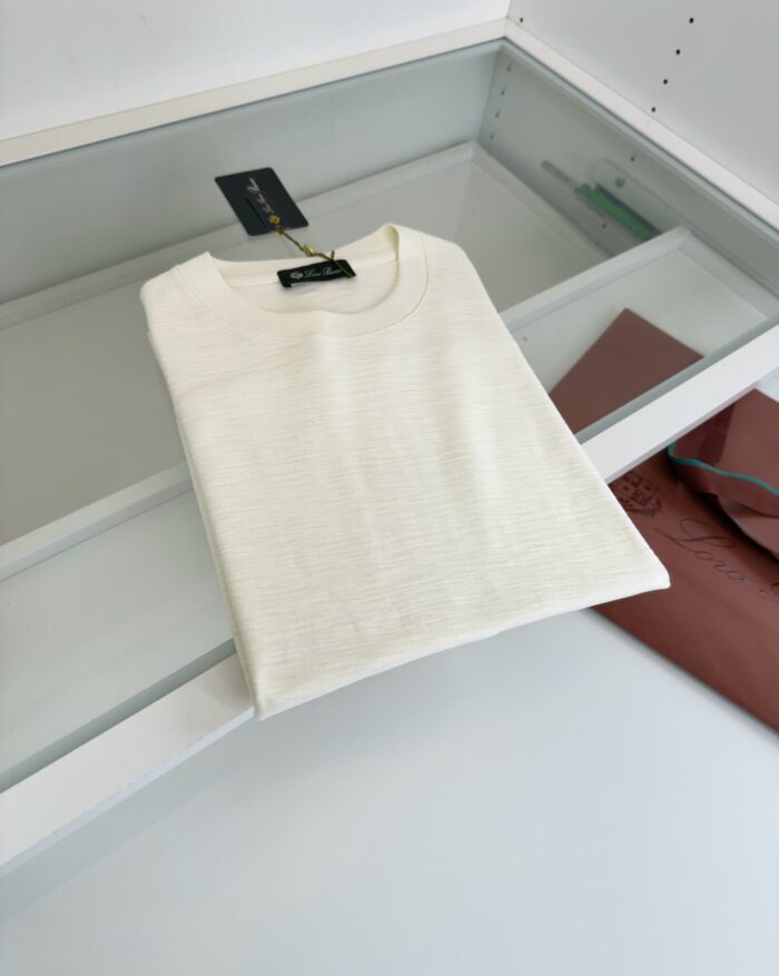 Maglietta beige casual su vetro, esposizione elegante in luce naturale, stile minimalista e moderno.