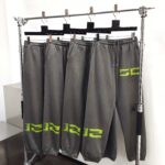 Pantaloni jogger grigi con logo neon verde su scaffale moderno in negozio di activewear.