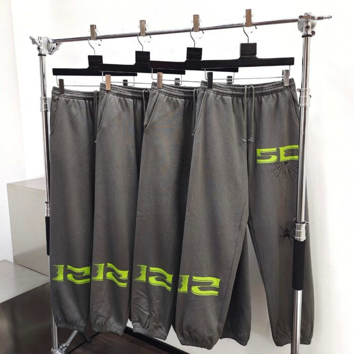 Pantaloni jogger grigi con logo neon verde su scaffale moderno in negozio di activewear.