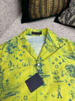 Camicia gialla con grafica blu e logo di lusso, stile casual e estivo.