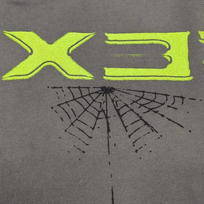 T-shirt con grafica rete di ragno e scritta neon verde, stile streetwear moderno e originale.