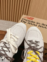 Sneaker Miu Miu e New Balance beige con lacci gialli, stile eleganza e moda contemporanea.