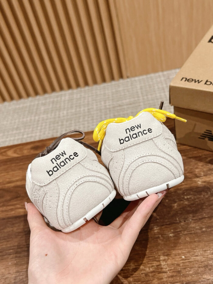 Scarpe New Balance moderne con dettagli colorati, sostenibili e stile sportivo su superficie di legno.