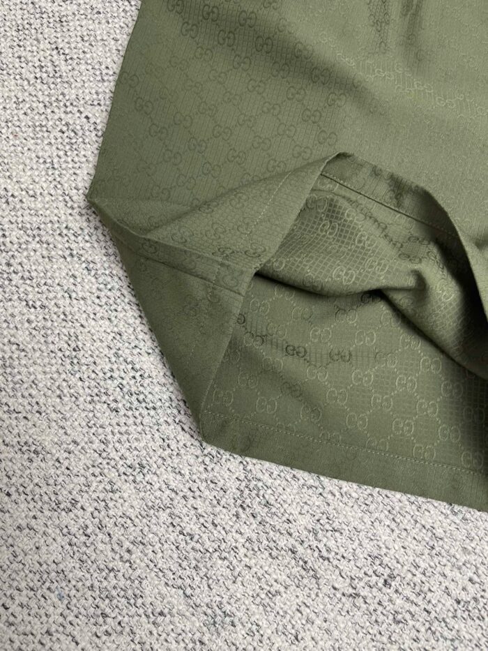 Dettaglio di tessuto verde oliva con pieghe e texture morbida, sfondo con contrasto elegante.
