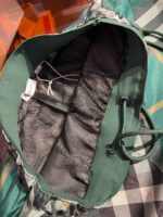 Zaino verde con scomparti in mesh, design casual e pratico per uso outdoor.